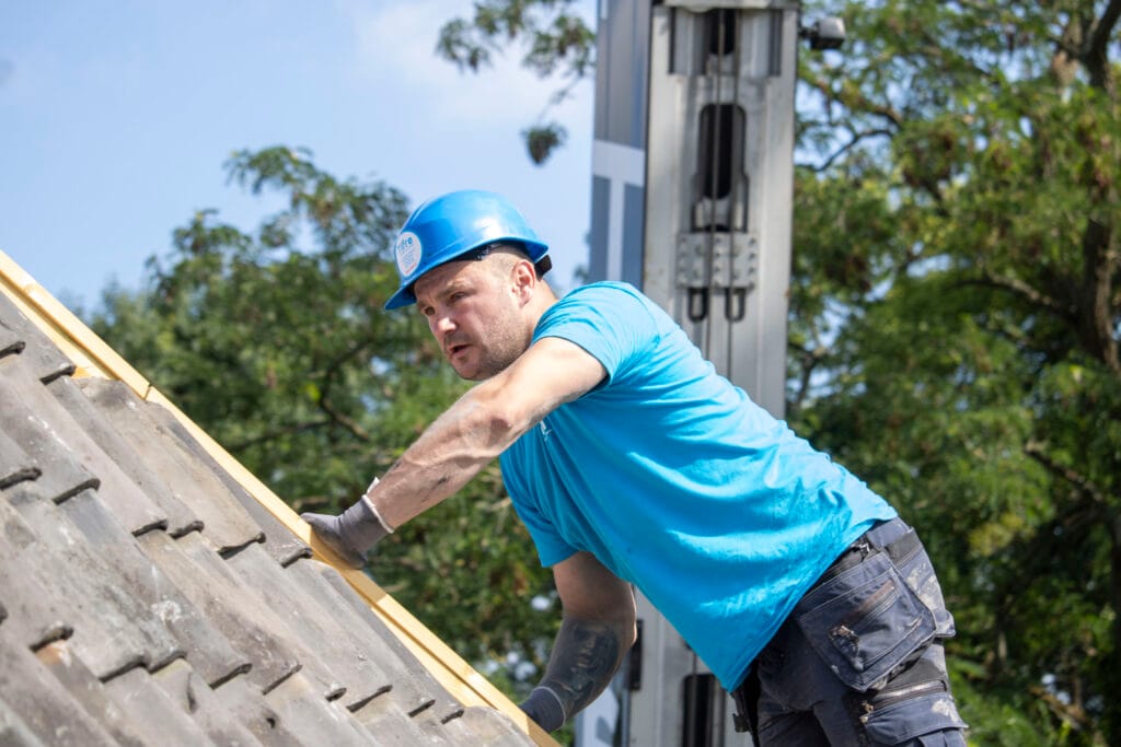 Dakwerker aan het werk om nieuwe rustieke pannen te leggen op werf van Tifre