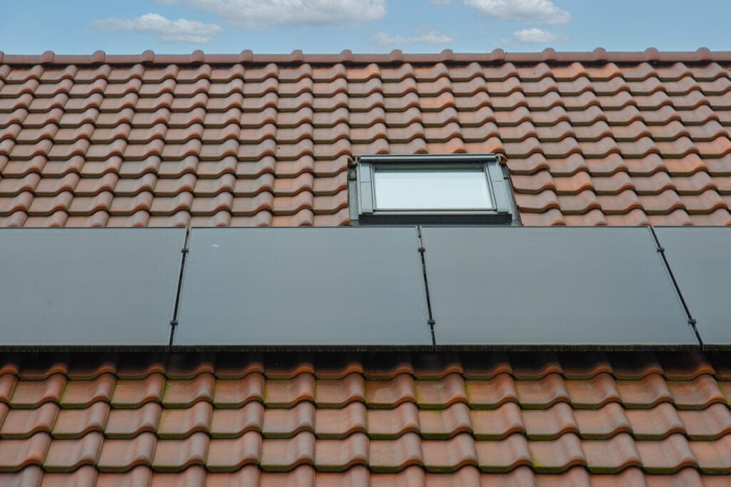zonnepanelen op een dak met rode pannen en velux