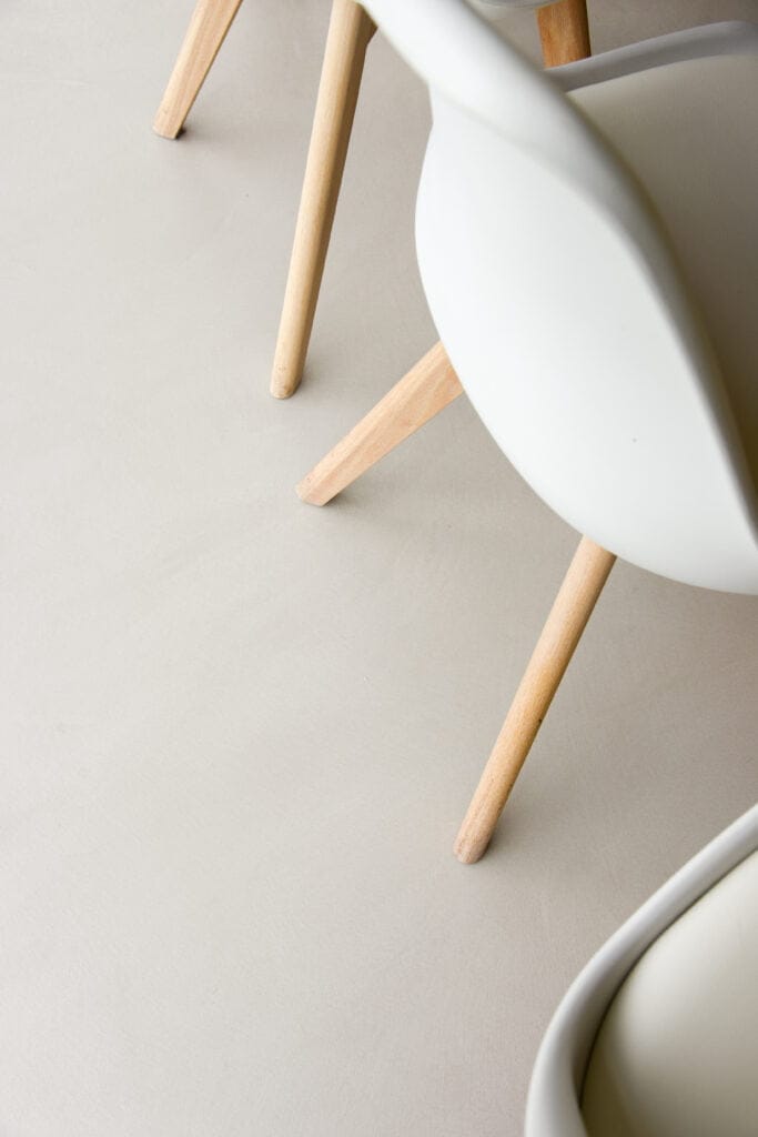 gietvloer detail met stoel met houten pootjes en witte leuning